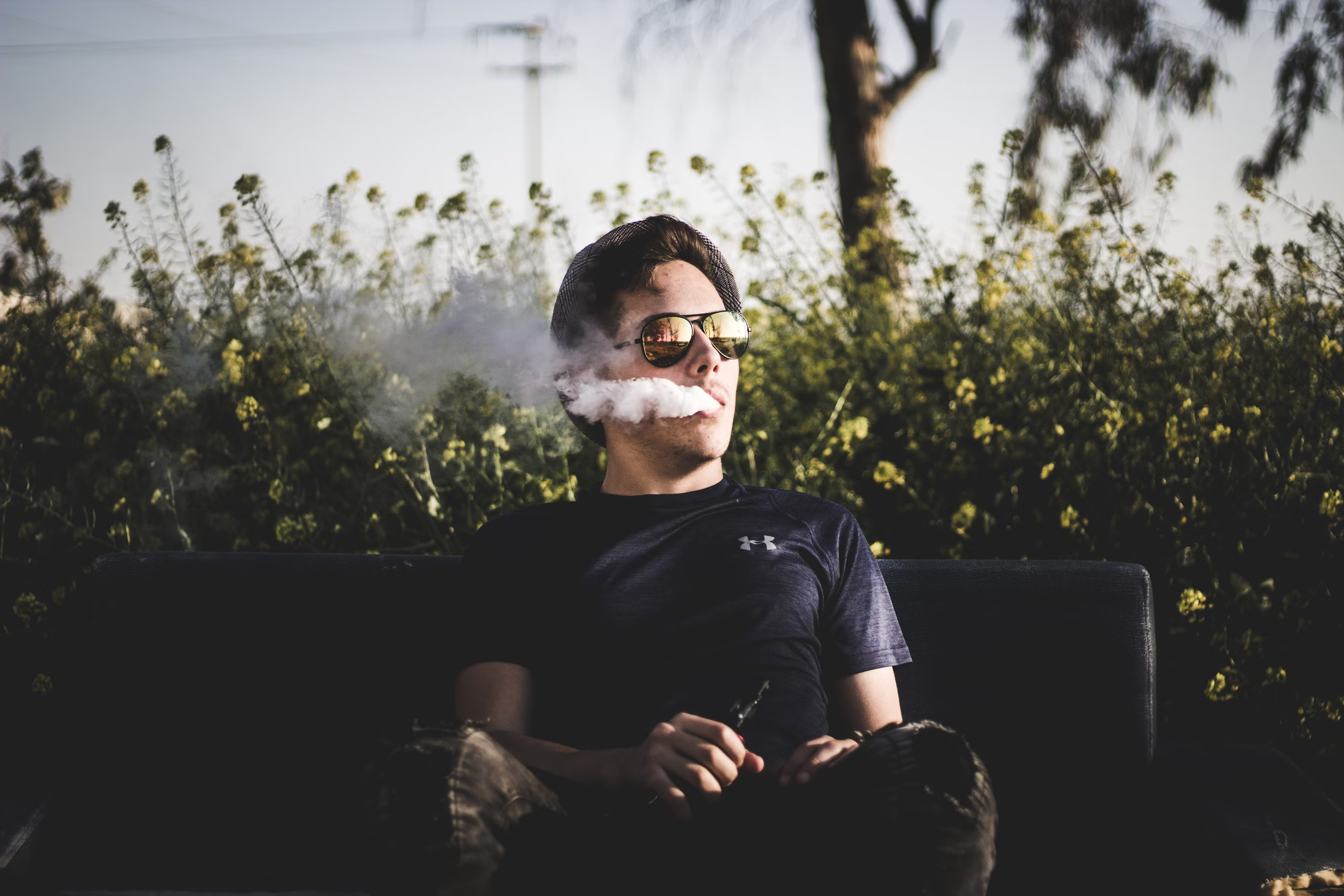 A man is vaping, looking relaxed.