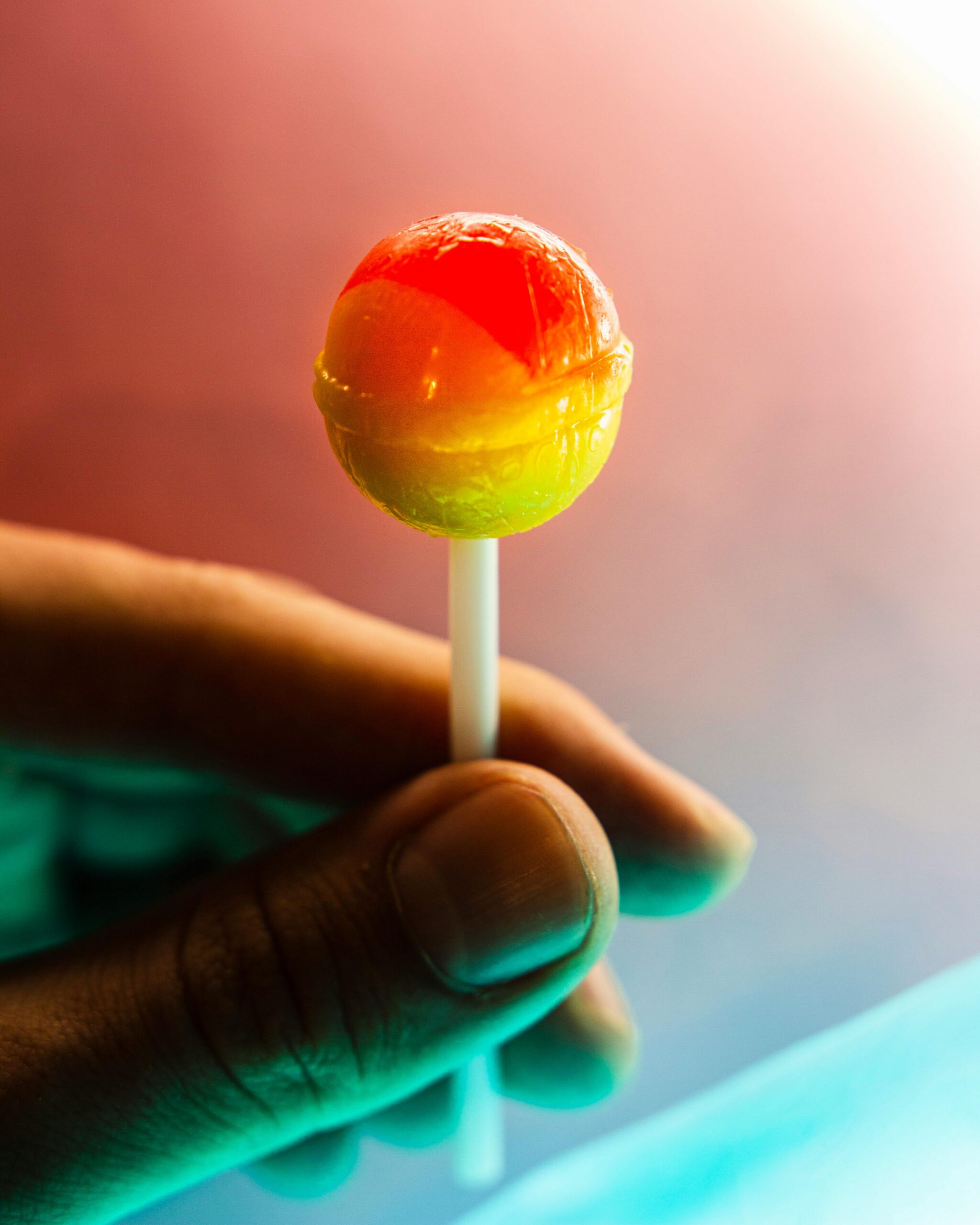 Vivid close-up of a hand holding a colorful lollipop, highlighting its delicious appeal.